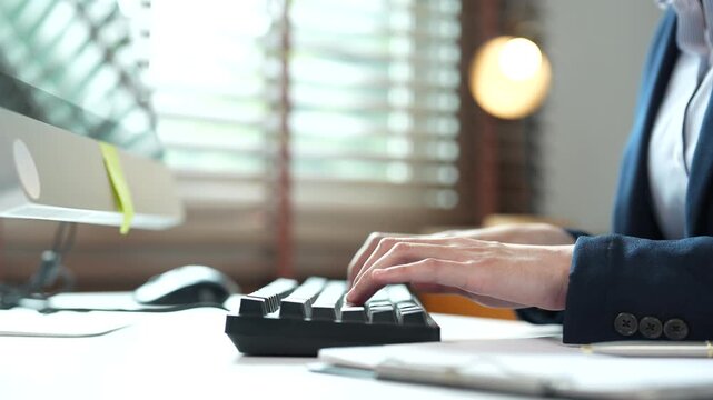 Professional business woman typing on computer keyboard at her desk, female office worker hands writing an email and sending a corporate message in a modern workplace