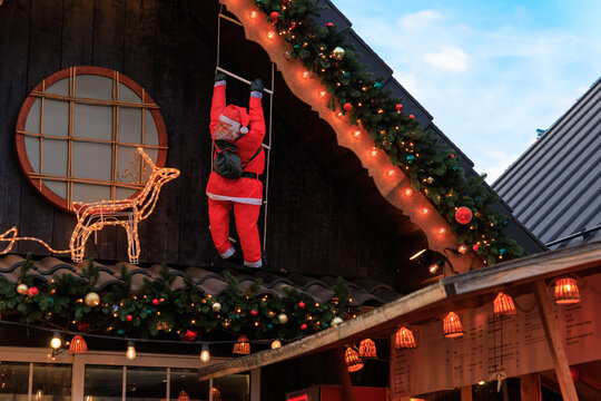 Santa Claus decoration climbing a roof at a festive market during the holiday Christmas season in December