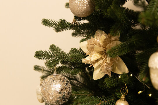 Decorations on a Christmas tree with silver ornaments and a gold flower in a cozy room during the holiday season