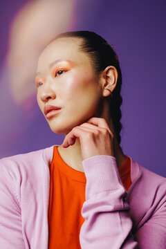 Asian woman beauty portrait in studio with calm thoughtful expression against purple background
