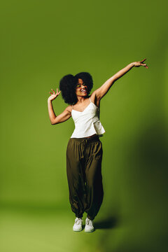 In a vibrant studio, a woman is dancing with joyful movement and freedom