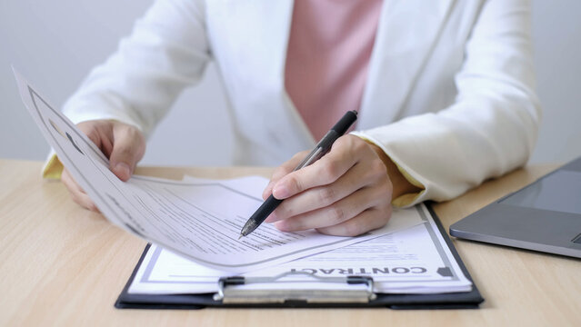 Businesswoman Reviewing Resume Documents at Office Desk with Laptop, Analyzing Candidate Information for Recruitment, Hiring and Job Interview Preparation