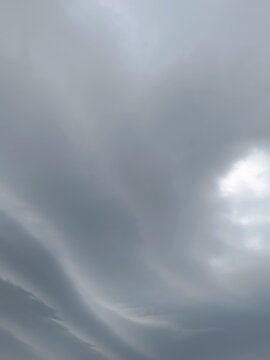 Overcast grey sky with thick clouds. Moody atmospheric weather background. Sun hidden behind dark storm clouds