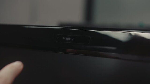 Close-up of finger sliding physical privacy shutter over laptop webcam. Concept of cybersecurity, online safety, digital privacy, protection from spying, hacking. Shooting in slow motion.