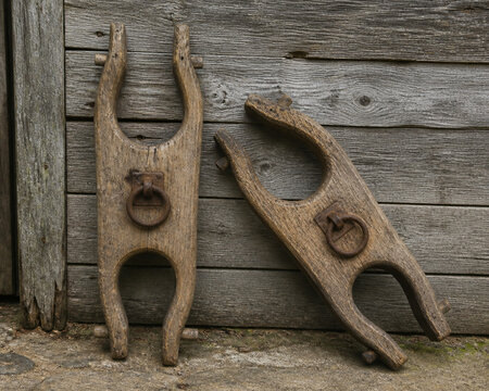 Two old wooden ox yokes with rusted iron rings against plank wall, agricultural heritage concept