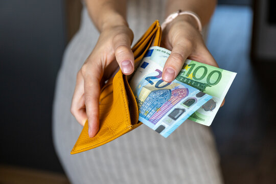 Close-up of female hands holding wallet with 20 and 100 euro bills. Budget planning, wealth and shopping concept.