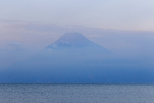 Misty blue volcano rising above a calm sea