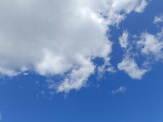 Obraz premium Bright blue sky with fluffy white cumulus clouds. Sunny daytime weather background with copy space