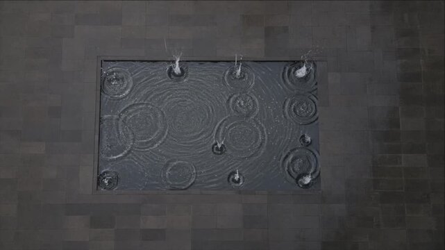 Cinematic city timelapse with dark gray pavement, ornate rectangular metal panel, abstract spiral and ripple pattern texture, moody urban wall, geometric aerial atmosphere, modern visual design