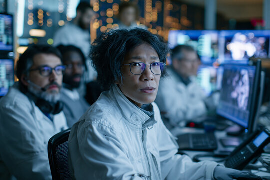 Focused Asian Scientist Working in High-Tech Control Room