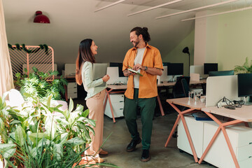 Fototapeta premium Colleagues collaborating and smiling in a modern green office, having a pleasant business conversation during work