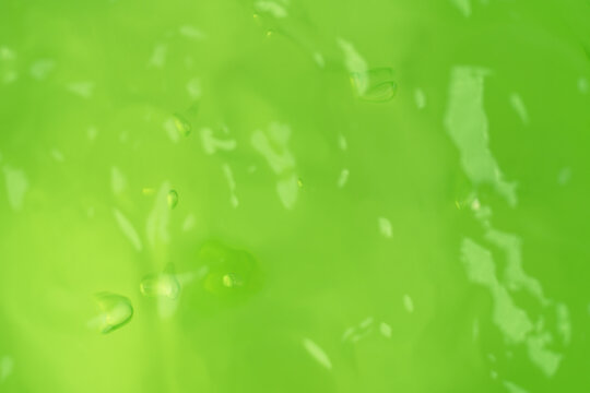Macro shot of green aloe vera gel texture with air bubbles and light reflections, selective focus with copy space on green background for skincare cosmetics, hydration, and organic beauty products.