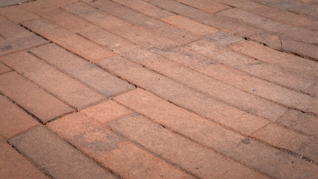 Rustic herringbone brick pavement texture with weathered red pavers