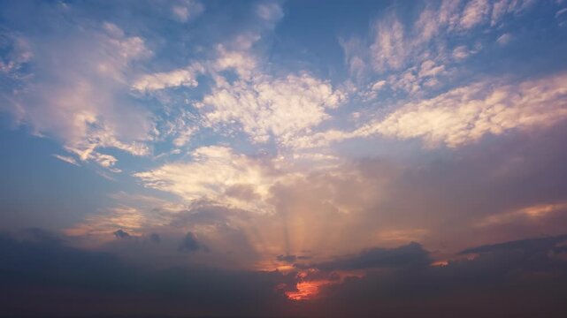 Time lapse of a glorious tranquil sunset with rays of sunlight and illuminated moving clouds. A calm nature scenery with the glowing sun and pleasant colors.