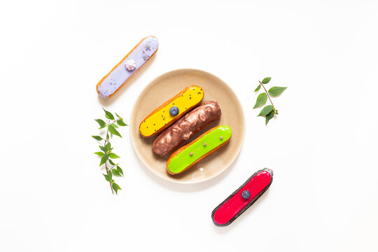French eclairs served on plate - colorful artisan dessert composition with soft daylight, top view food photography