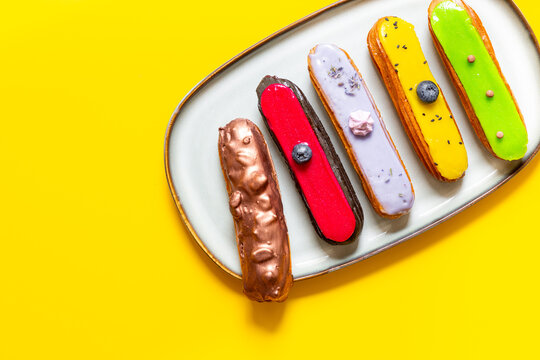 French eclairs served on plate - colorful artisan dessert composition with soft daylight, top view food photography