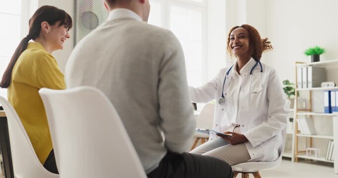 Doctor couple consultation pregnancy planning healthcare advice. Warm clinic meeting as a physician explains options, answers questions and supports parents. Clear family planning concept theme.