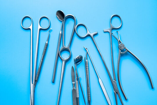A lot of stainless surgical instruments and tools on blue table, top view. Medical background