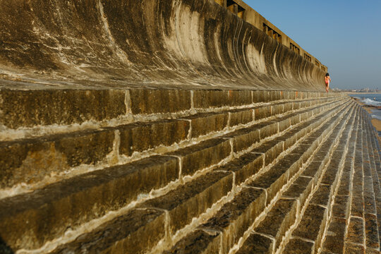 Rear view of a Girl walking Along Seaside Wall