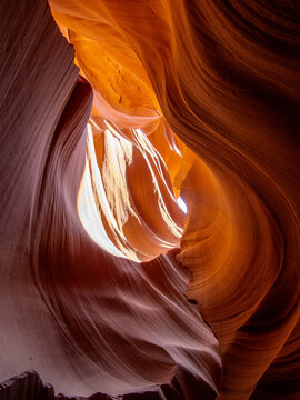 Upper Antelope Canyon sandstone waves, Page, Arizona. Close up details of undulating rock textures and forms with natural light filtering down. Vertical composition.