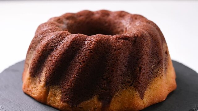 Chocolate bundt cake rotating on white background