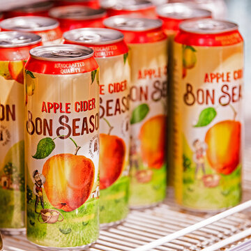 Multiple Bon Season apple cider cans displayed in a refrigerator. Sparkling fruit beverage packaging with apple illustration
