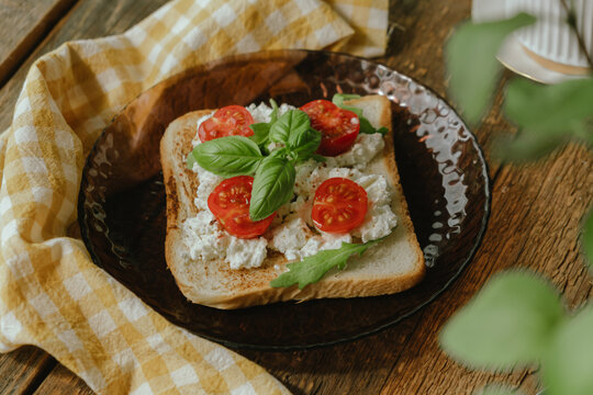 Sandwich or italian bruschetta. Breakfast in rustic style. Italian toast topped with cream cheese, tomato and fresh basil leaves.