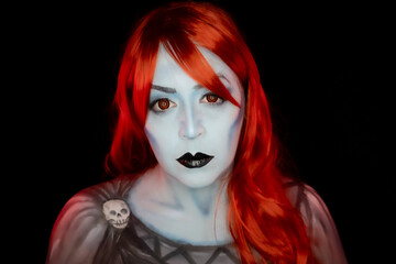 Obraz premium Fantasy portrait of a woman with vivid colored hair, blue-toned skin, red eyes and dramatic dark makeup, creating a striking supernatural character on a dark background.