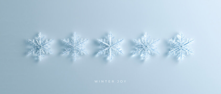 Five transparent glass snowflakes in a row on a light blue background. Minimalist winter holiday 