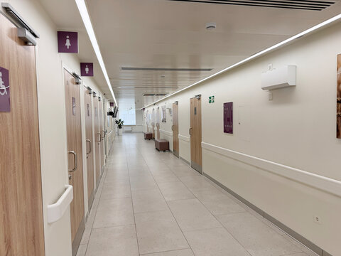 Hospital corridor displays several restroom doors with clear signage, modern decor, and bright lighting, ensuring accessibility for patients and visitors