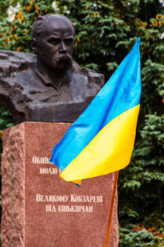 Ukrainian blue and yellow flag fluttering near Taras Shevchenko statue outdoors