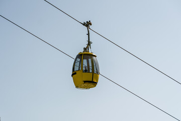 Yellow cable car gondola traveling across alpine mountain scenery in the Dolomites, Italy, representing mountain transportation and tourism. © Anastasia