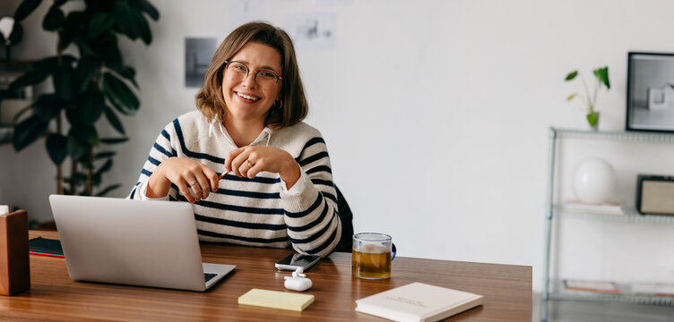 During a break, the woman stays at her laptop in a calm home office workspace