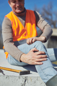 Construction worker having a accident and injured knee and leg on a construction site outdoors.