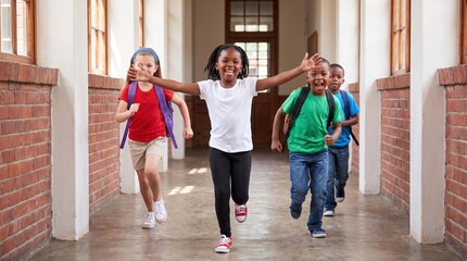 Obraz premium Four cheerful children with backpacks run down a school corridor between brick walls, smiling; girl in front with arms wide, boys and another girl behind