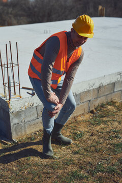 Construction worker having a accident and injured knee and leg on a construction site outdoors.