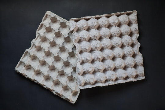 Closeup of pressed recycled cardboard egg tray texture, highlighting rough fibers, natural paper pulp, sustainable packaging, and earthy material details.