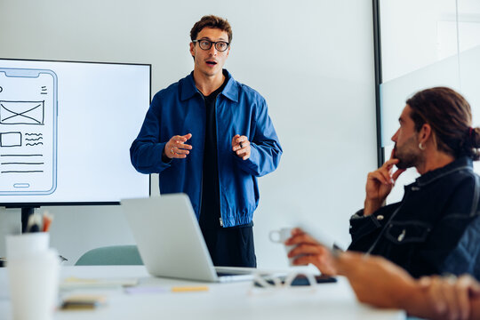 Designers present user flow to team in meeting