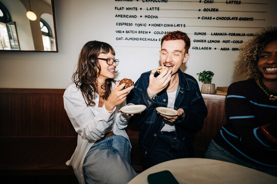 Friends enjoying eating pastries together in a cafe