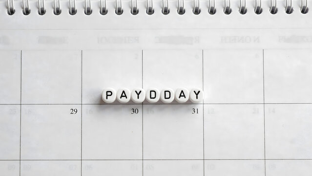 Alphabet letter beads spelling payday placed on a white wall calendar page