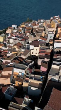 Vertical, aerial view of the Castelsardo, a medieval town in northern Sardinia (Sassari province) on the Gulf of Asinara. It features cascading, colorful houses and a historic fortress.
