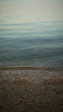 Vertical video, peaceful early morning beach scene along the Croatian coast. Concept of calm sea travel, serene nature background, Adriatic vacation, and quiet morning tranquility. 4K.