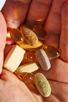 Close-Up of Hand Holding Assorted Dietary Supplements and Vitamin Pills