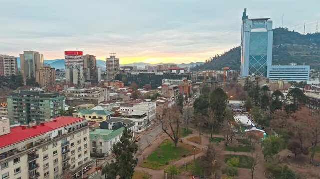 Aerial View over Bustamante Urban Park in Santiago de Chile Toward San Crist&oacute;bal Hill and Skyscraper Telef&oacute;nica at Sunset