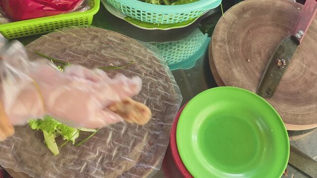 Top-down view of adding shredded mango and removing grilled pork sausage from bamboo skewer onto rice paper with vegetables for nem nuong, food preparation stock footage