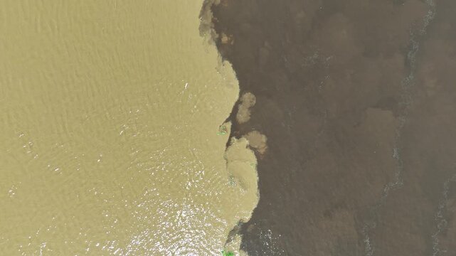 Cinematic top-down footage of the swirling currents at the Encontro das Aguas where two contrasting Amazonian rivers meet.