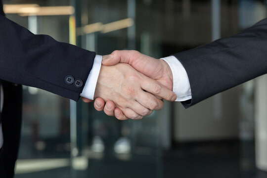 Two business people shaking hands in a close-up view, symbolizing a successful professional partnership, collaboration, and agreement after a meeting or negotiation