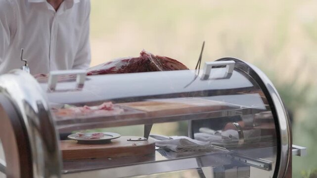 Professional caterer slicing cured ham outdoors