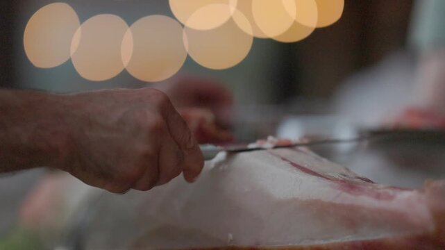 Professional chef slicing cured spanish ham prosciutto