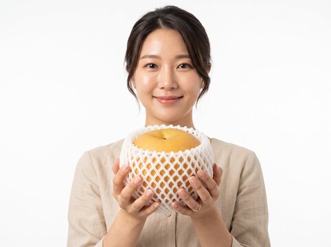 Woman presenting premium giant Korean Asian pear in protective foam net on white